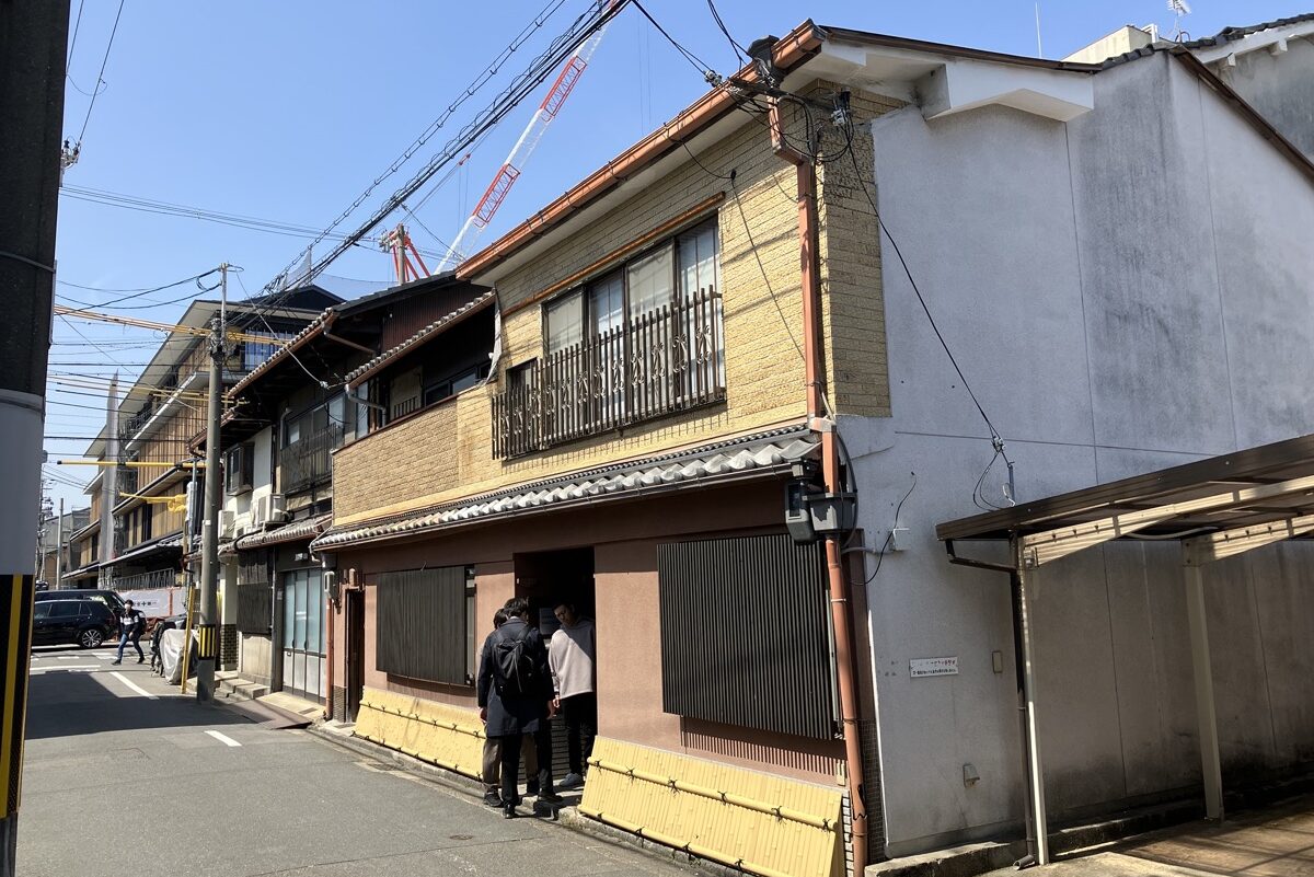 改修前の外観。2階建ての木造の建物が、両隣の建物と接して道沿いに並んでいる