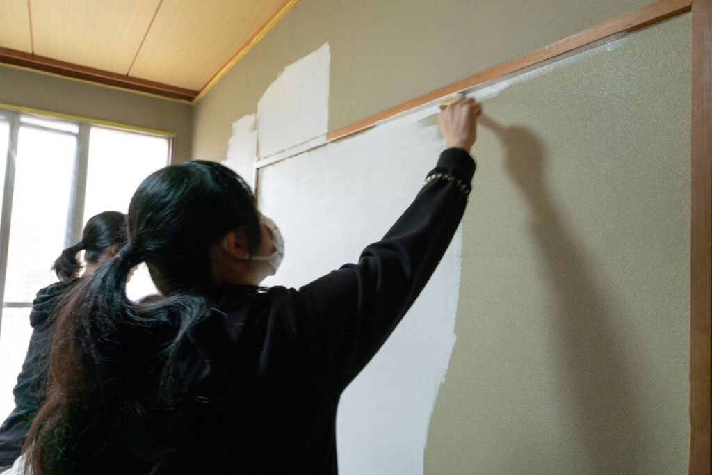 刷毛とローラーで塗装する子どもたち